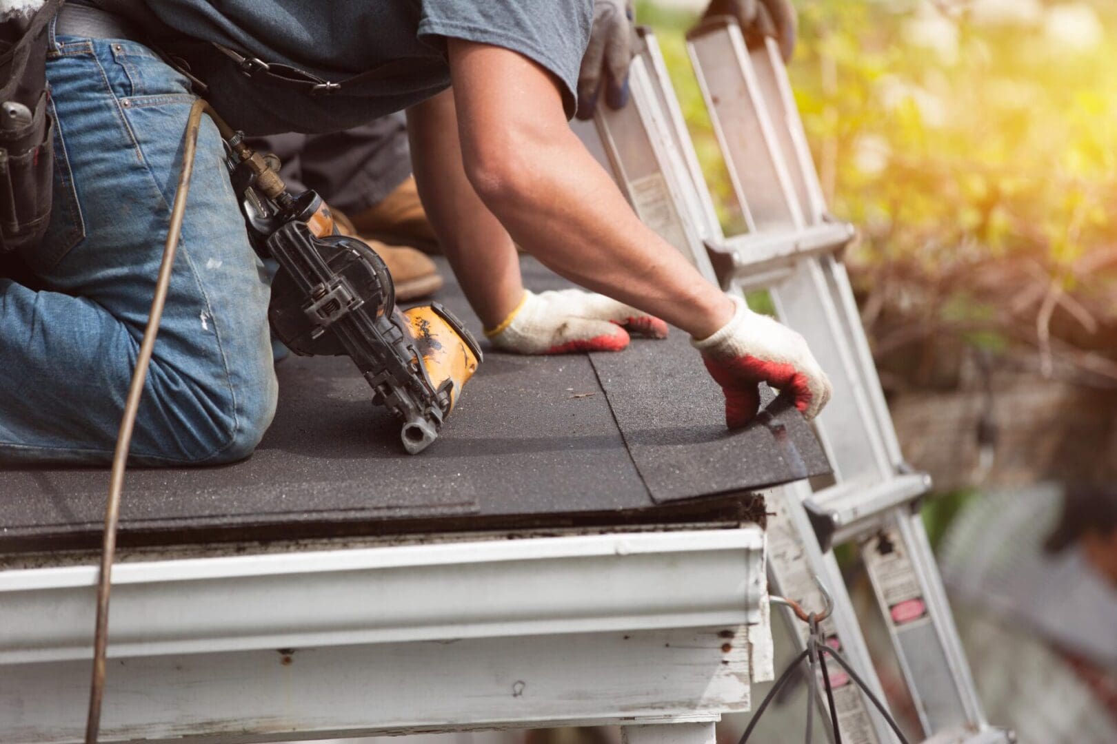 Worker installing roofing shingles on a house.