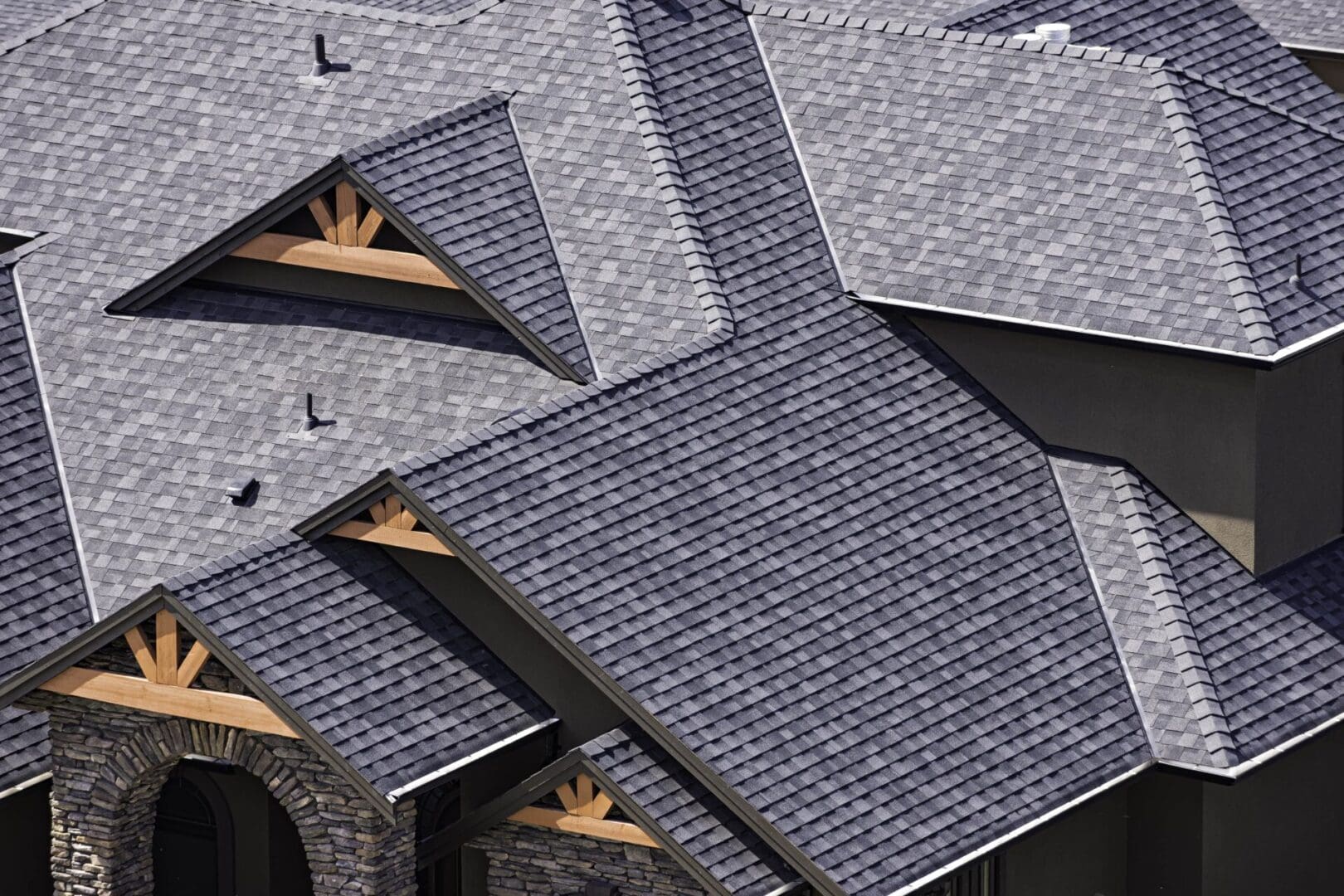 Aerial view of a complex roof structure with gray shingles and wooden accents.